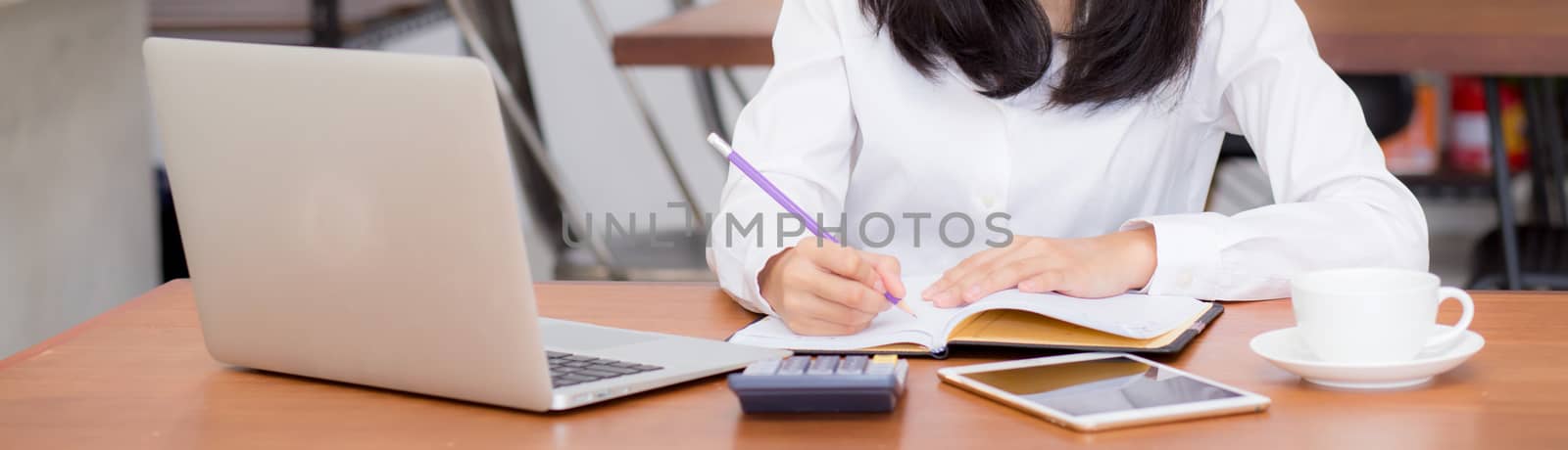 Closeup banner asian woman writing on notebook on table with laptop, girl work at coffee shop, freelance business concept.
