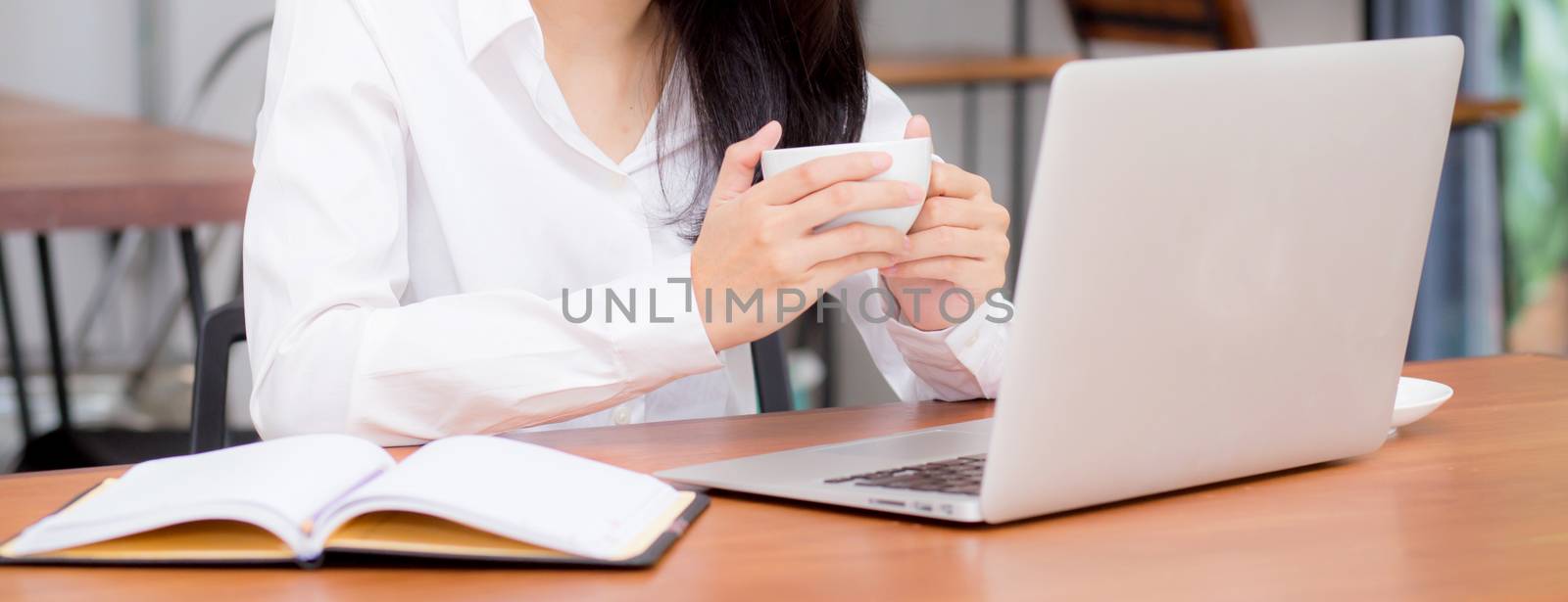closeup banner website asian young woman working online on laptop sitting at coffee shop, professional female freelancer using notebook computer with connect to internet for distance job.