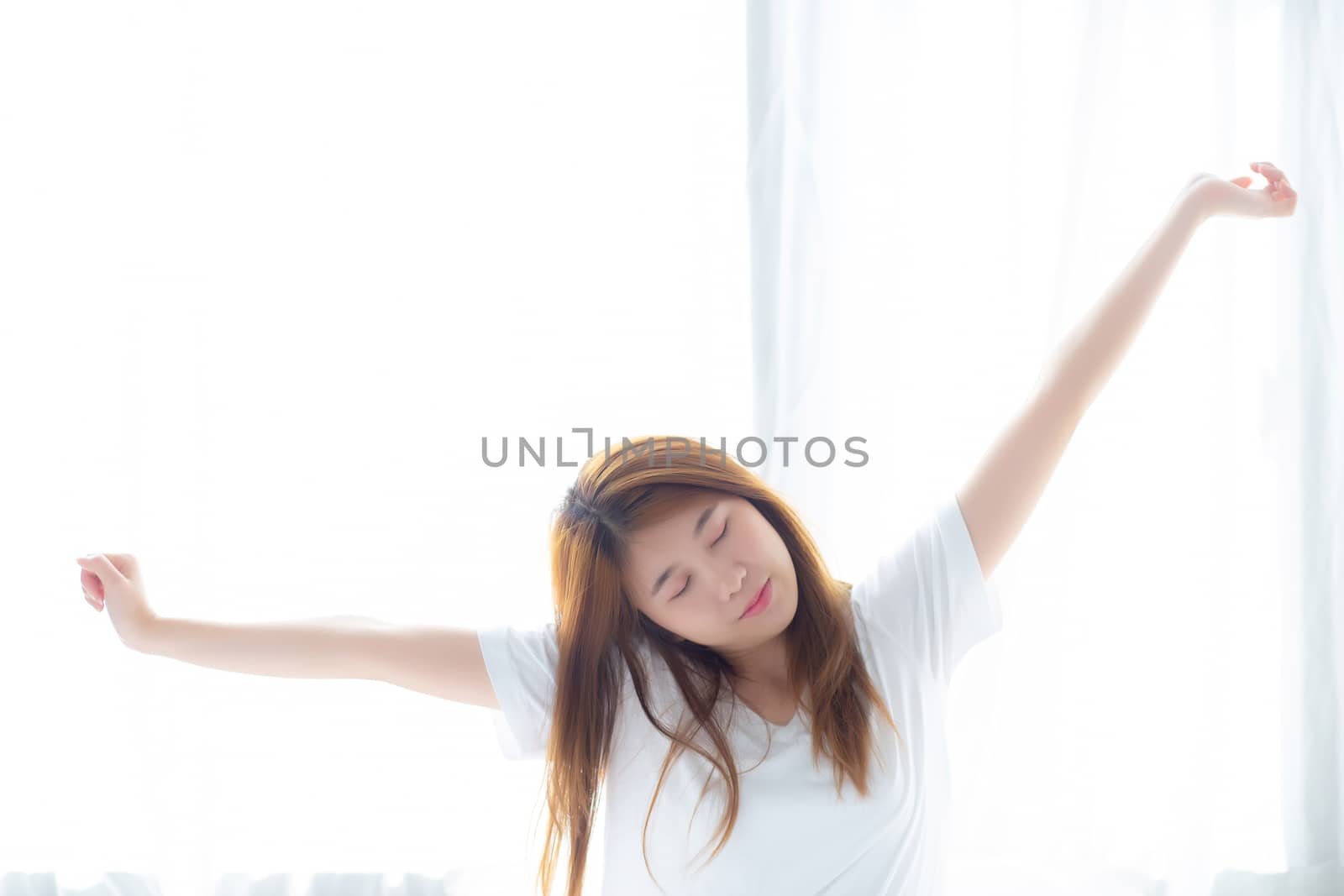 Beautiful of portrait young asian woman stretch and relax in bed after wake up morning at bedroom, new day and resting for wellness, lifestyle concept.