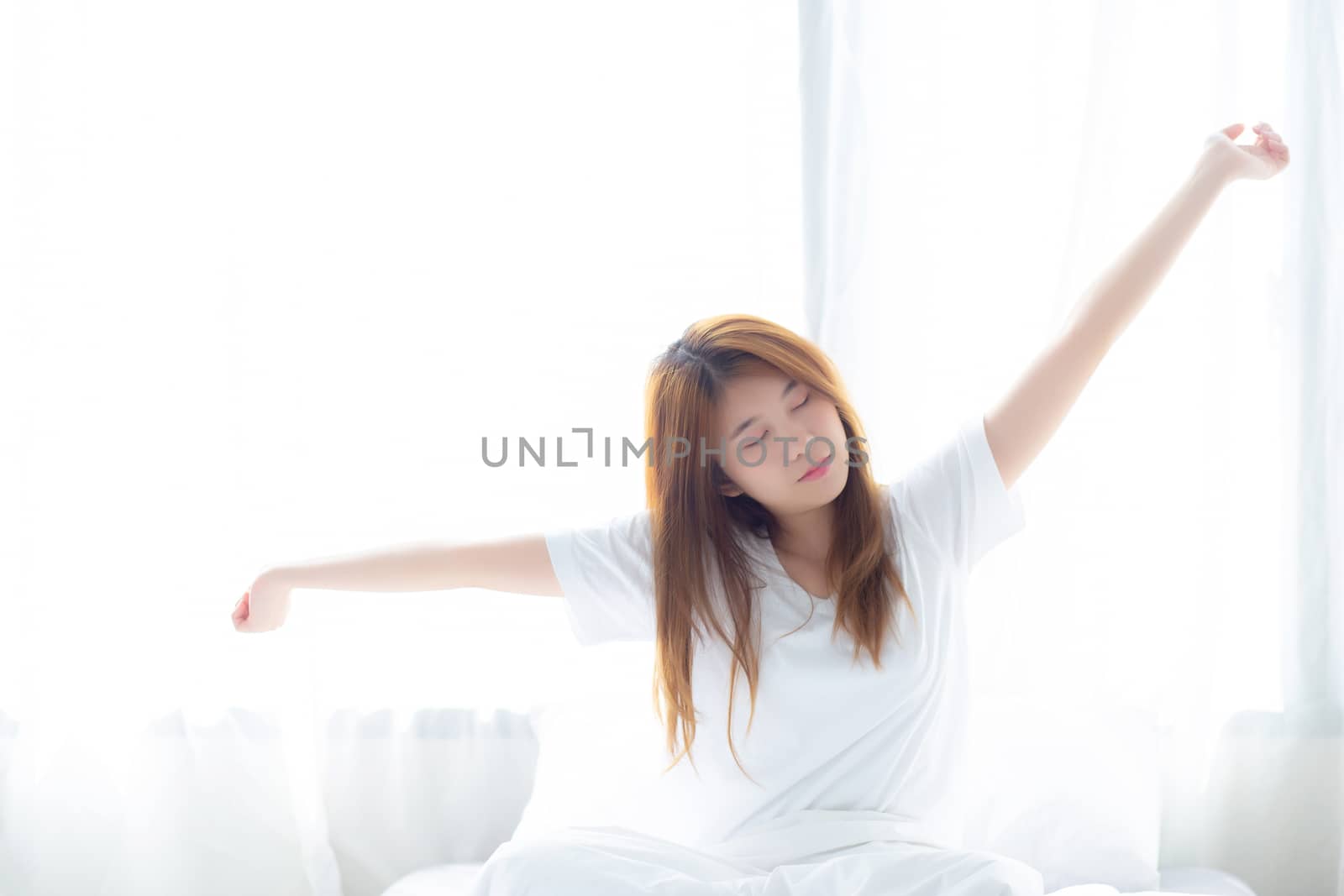 Beautiful of portrait young asian woman stretch and relax in bed after wake up morning at bedroom, new day and resting for wellness, lifestyle concept.