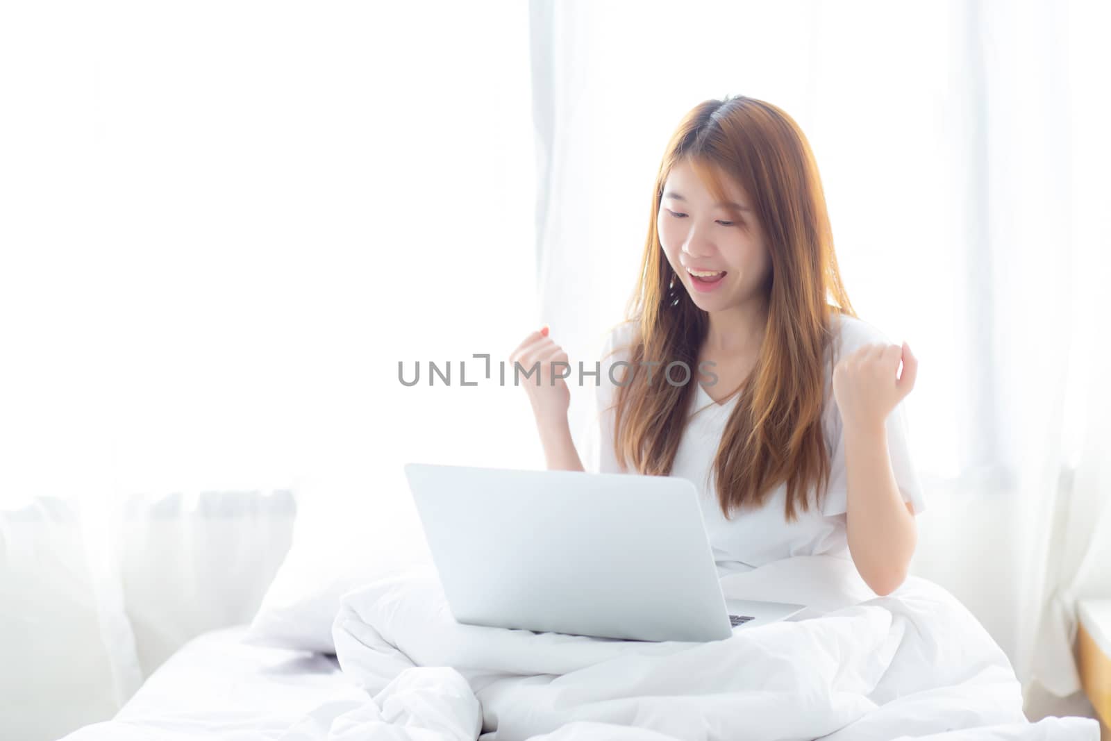 Beautiful happiness young asian woman using laptop work with suc by nnudoo