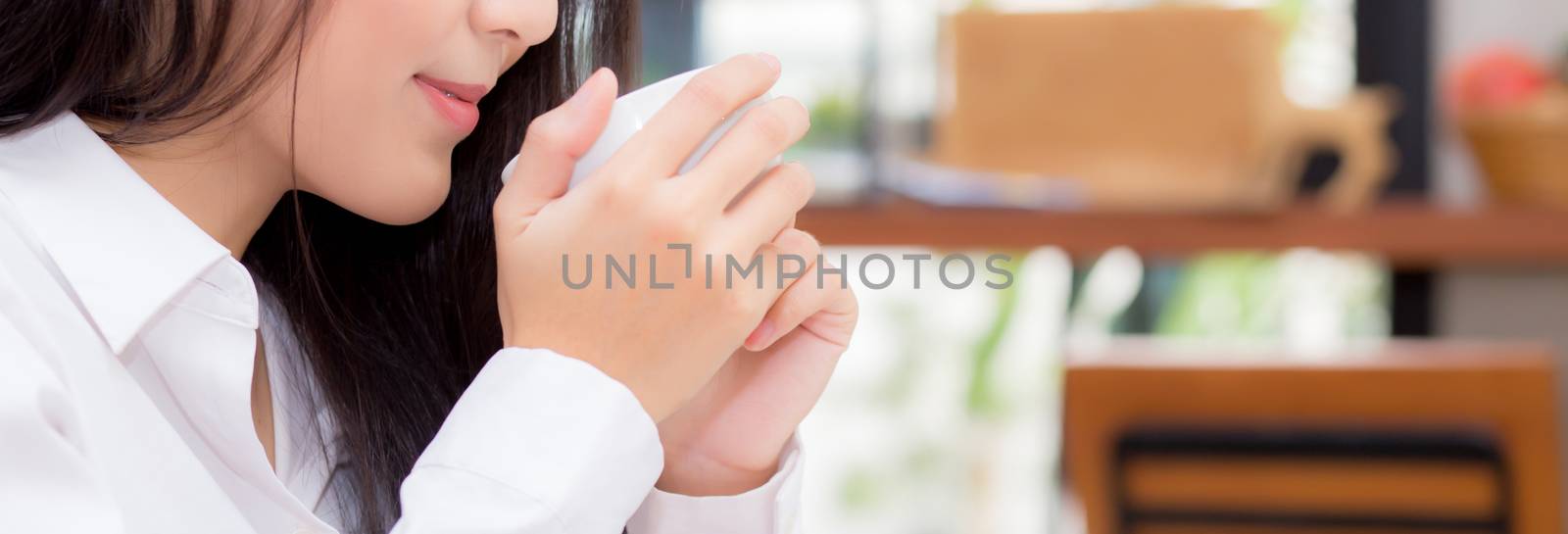 Closeup banner website young asian woman drinking coffee and smile in the morning at cafe, girl sitting in coffee shop for breakfast and leisure during free time.
