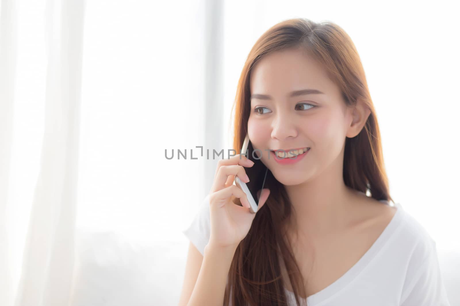 Beautiful of portrait young asian woman talking smart mobile pho by nnudoo