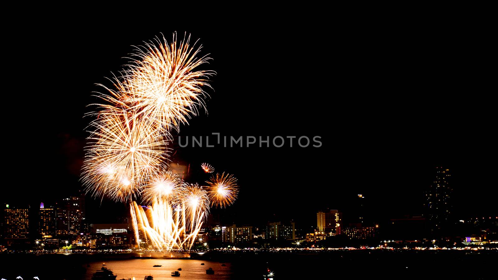 Many flashing fireworks with night cityscape background celebrate New Year.