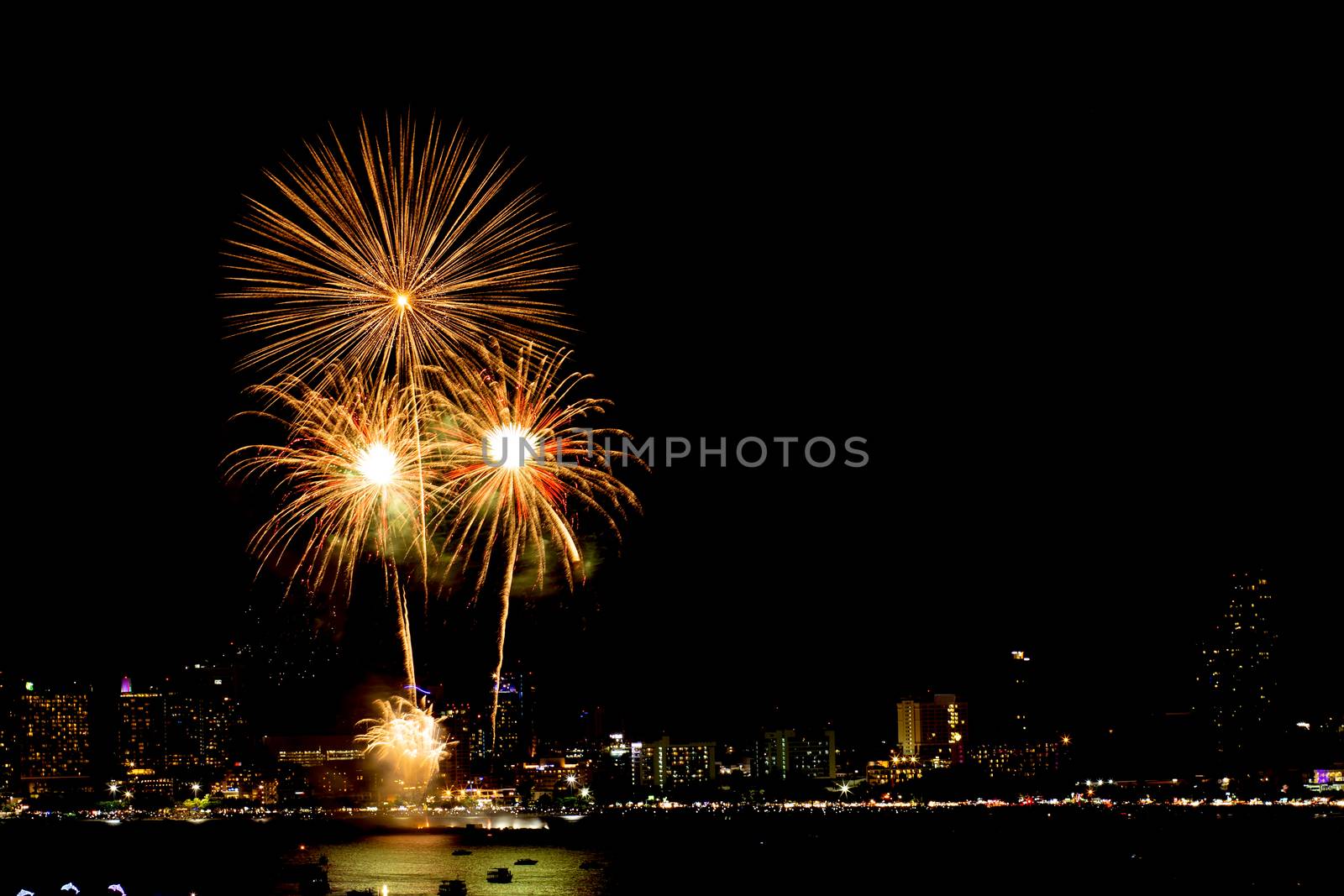 Many flashing fireworks with night cityscape background celebrate New Year.