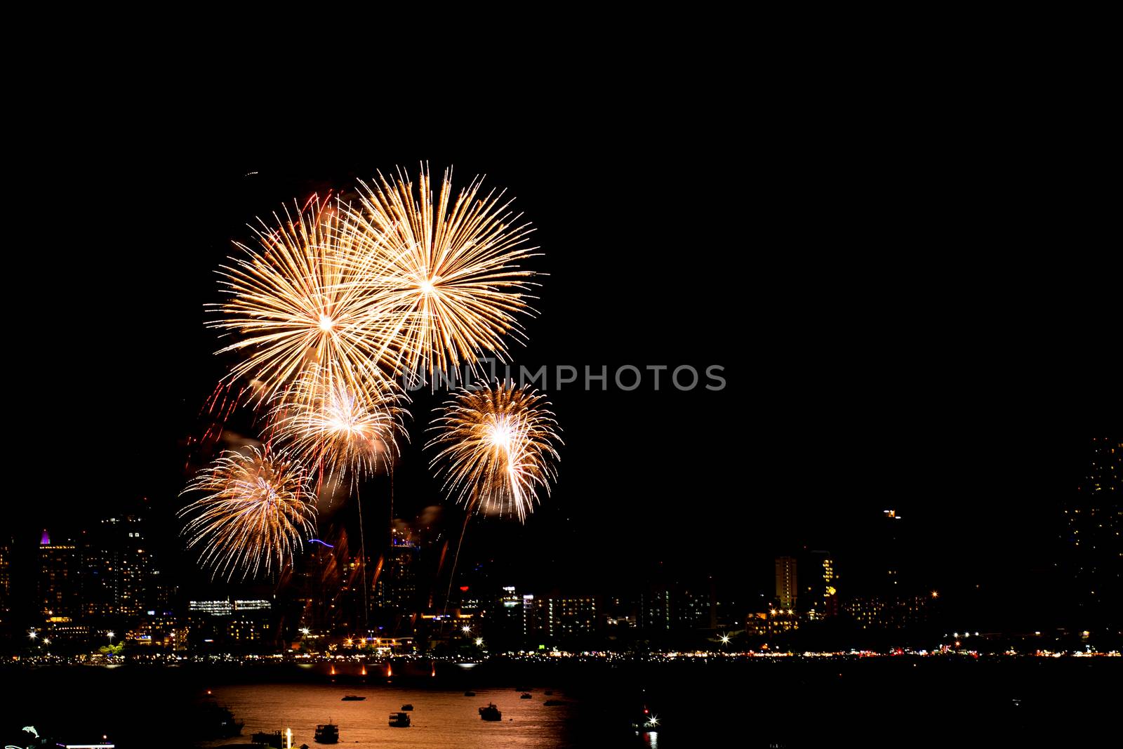 Many flashing fireworks with night cityscape background celebrate New Year.
