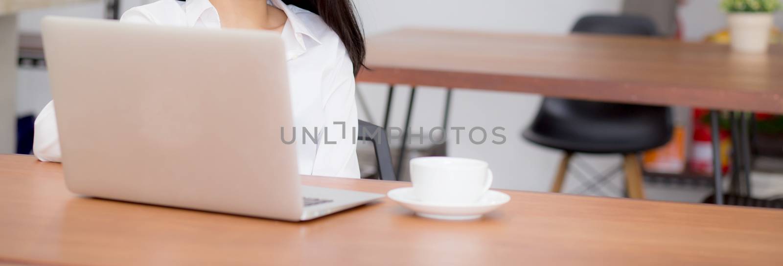 Closeup banner website asian young woman working online on laptop sitting at coffee shop, professional female freelancer using notebook computer with connect to internet for distance job.