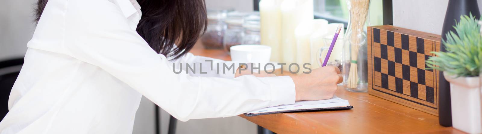 Closeup banner website business asian young woman writing on notebook on table, girl work at coffee shop, freelance business concept.