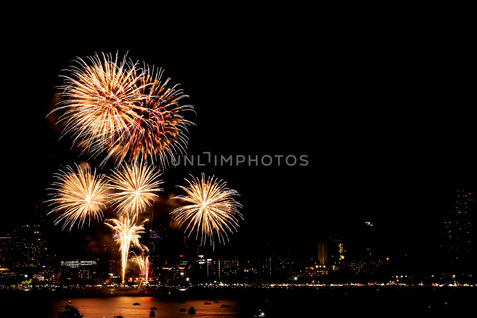 Many flashing fireworks with night cityscape background celebrate New Year.