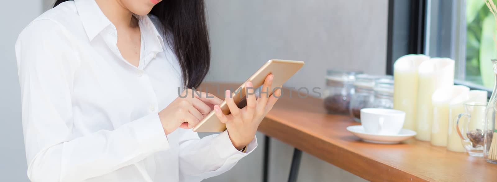 Closeup banner website asian young businesswoman holding tablet, woman looking mobile phone and working internet online coffee shop, career freelance business concept.