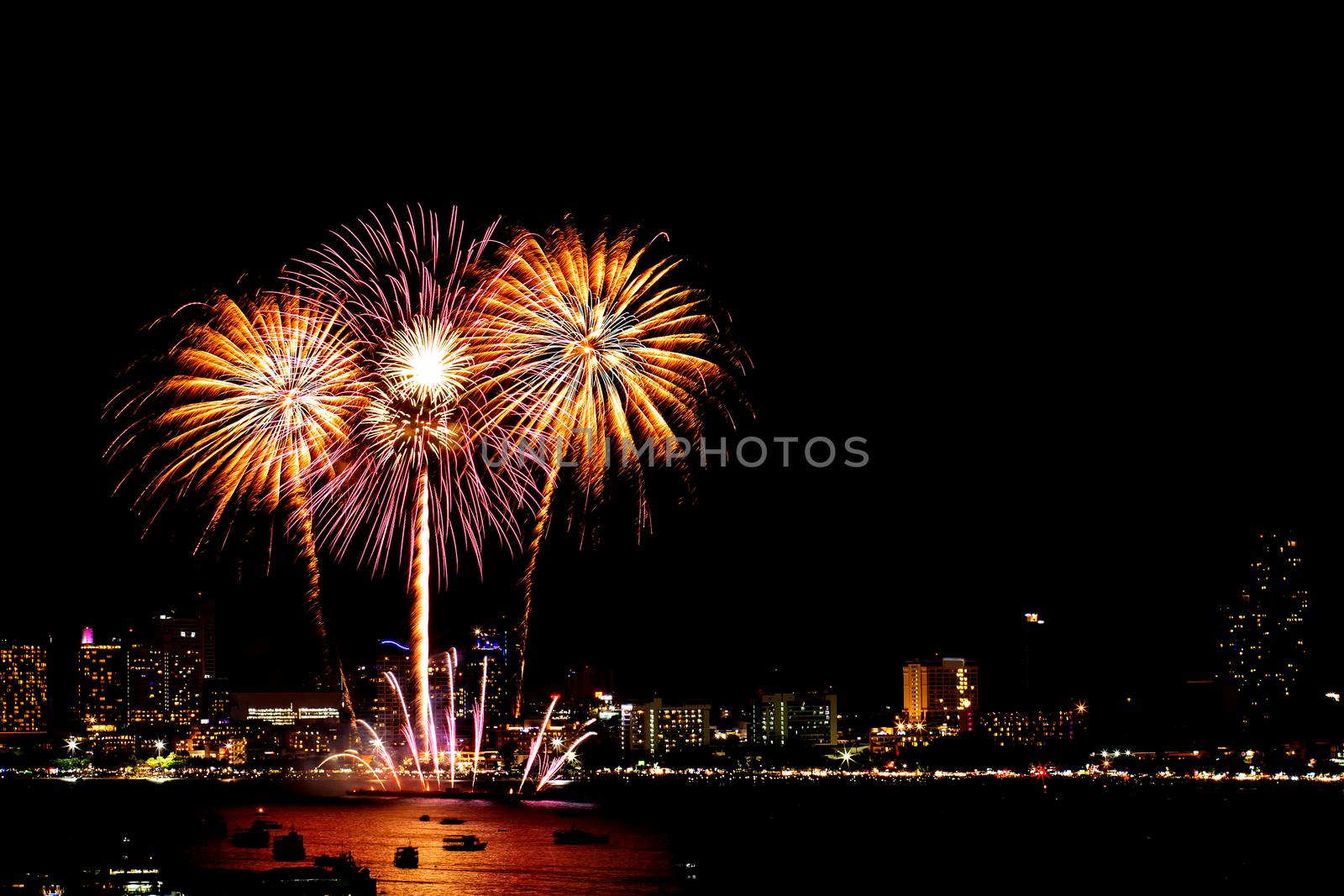 Many flashing fireworks with night cityscape background celebrate New Year.