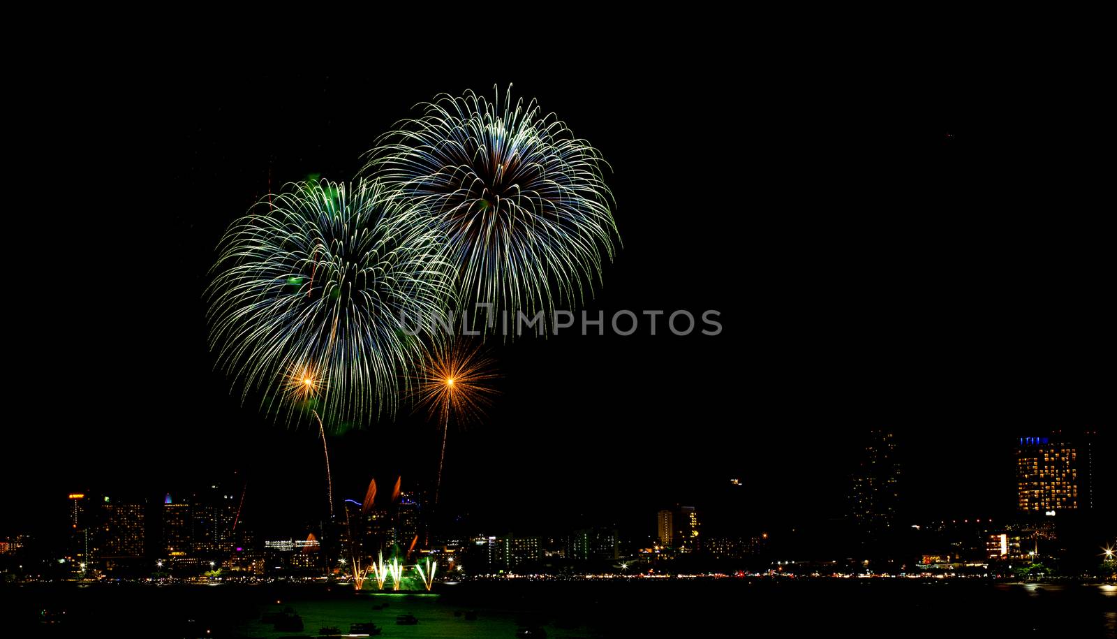 Many flashing fireworks with night cityscape background celebrate New Year.