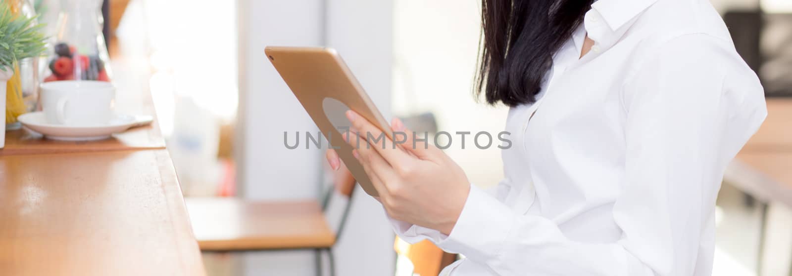 Closeup banner website asian young businesswoman holding tablet, woman looking mobile phone and working internet online coffee shop, career freelance business concept.