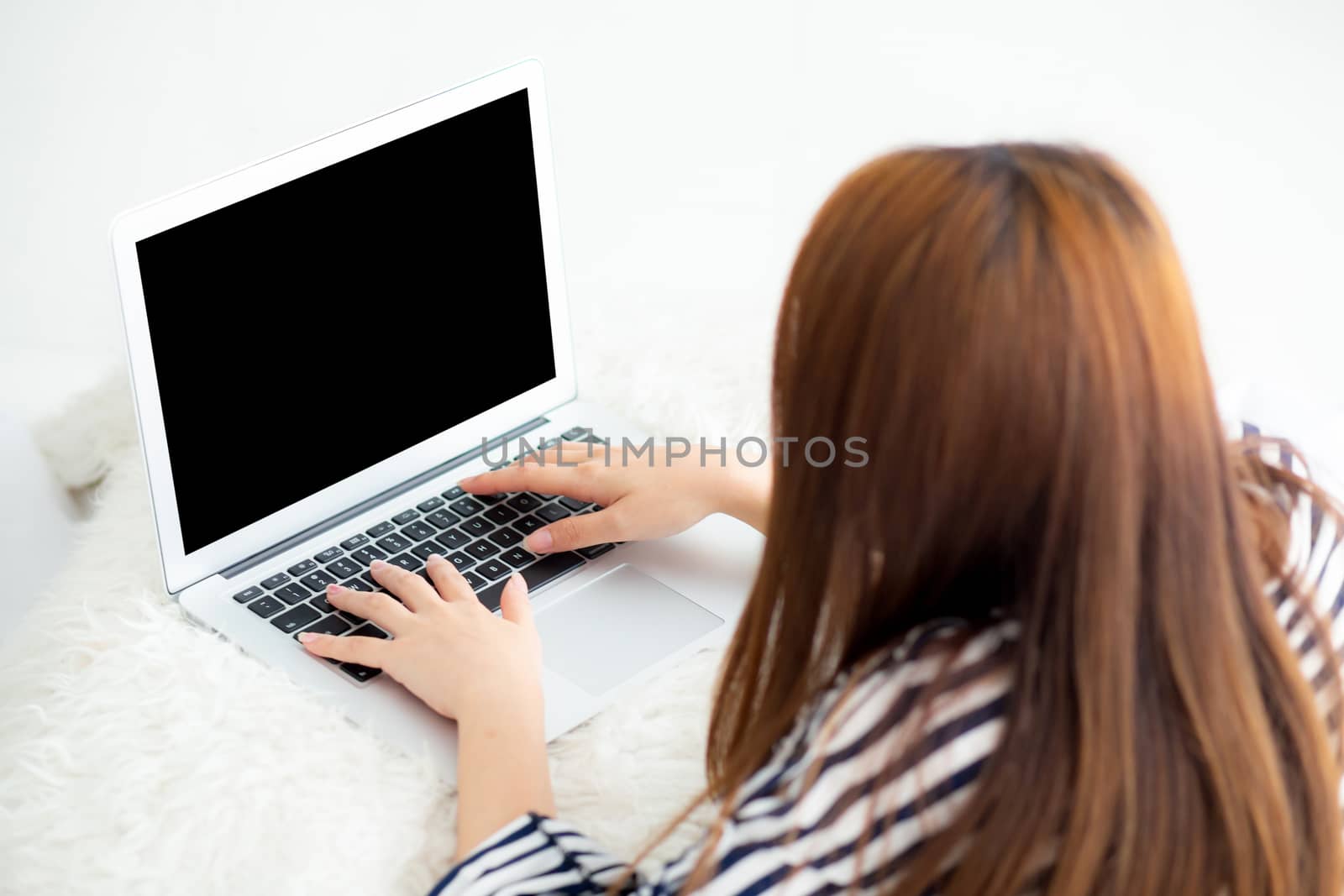 Beautiful asian young woman lying on bed using laptop at bedroom by nnudoo