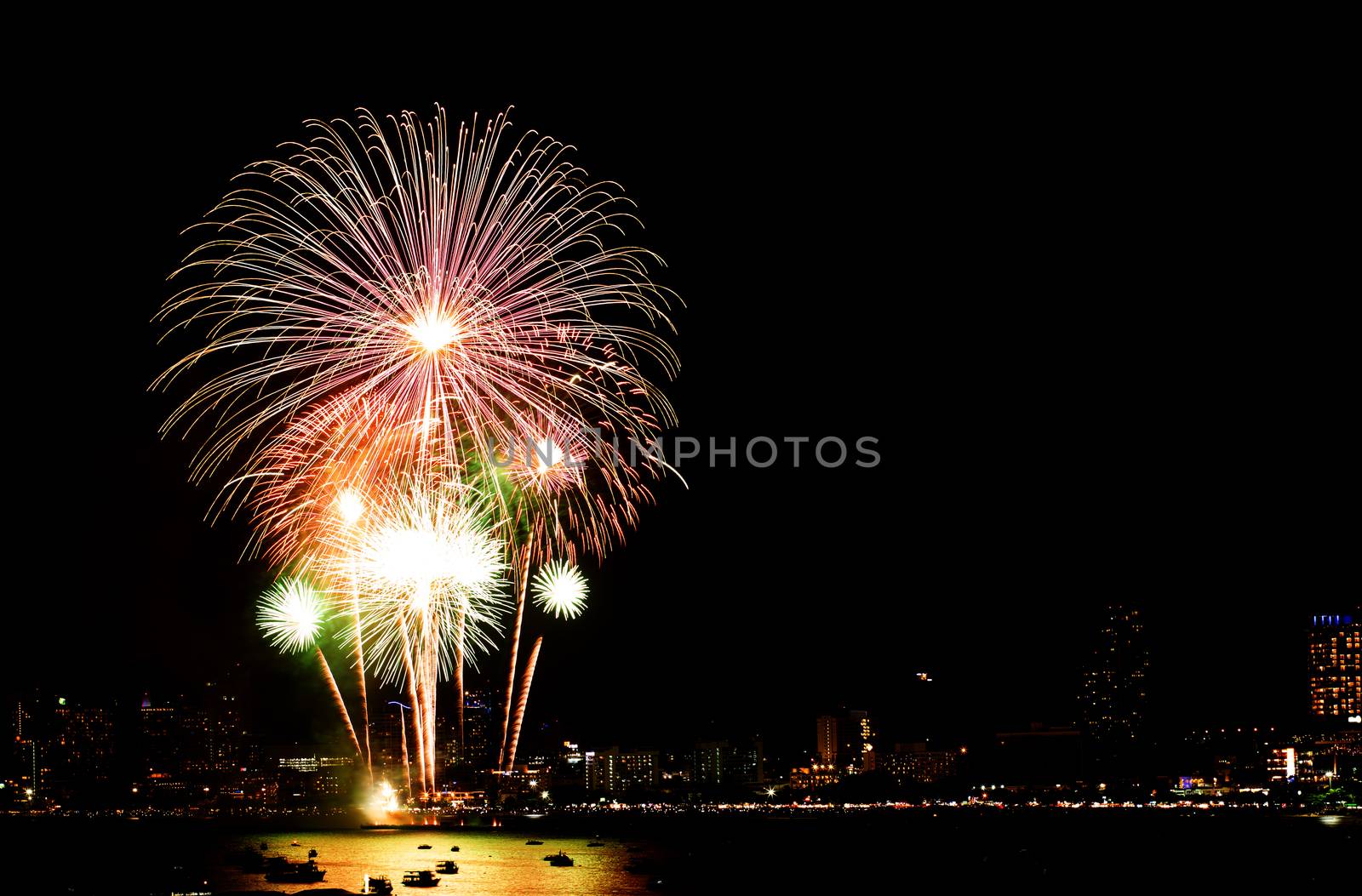 Many flashing fireworks with night cityscape background celebrate New Year.