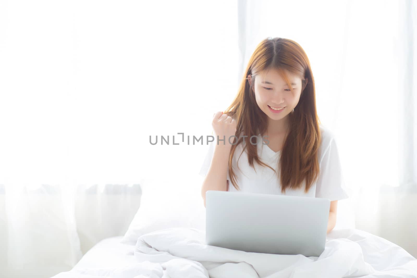 Beautiful happiness young asian woman using laptop work with suc by nnudoo