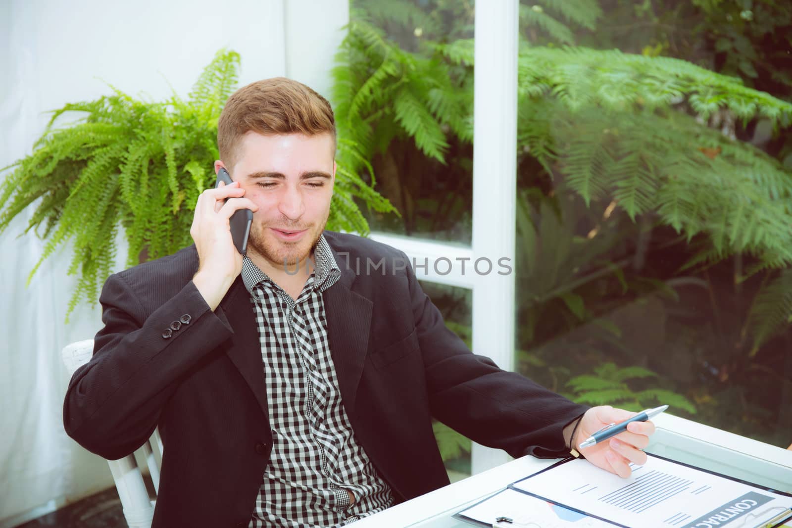 Businessman talking on smart mobile phone with document on desk with smiling, man call phone at office with professional, business and communication concept.