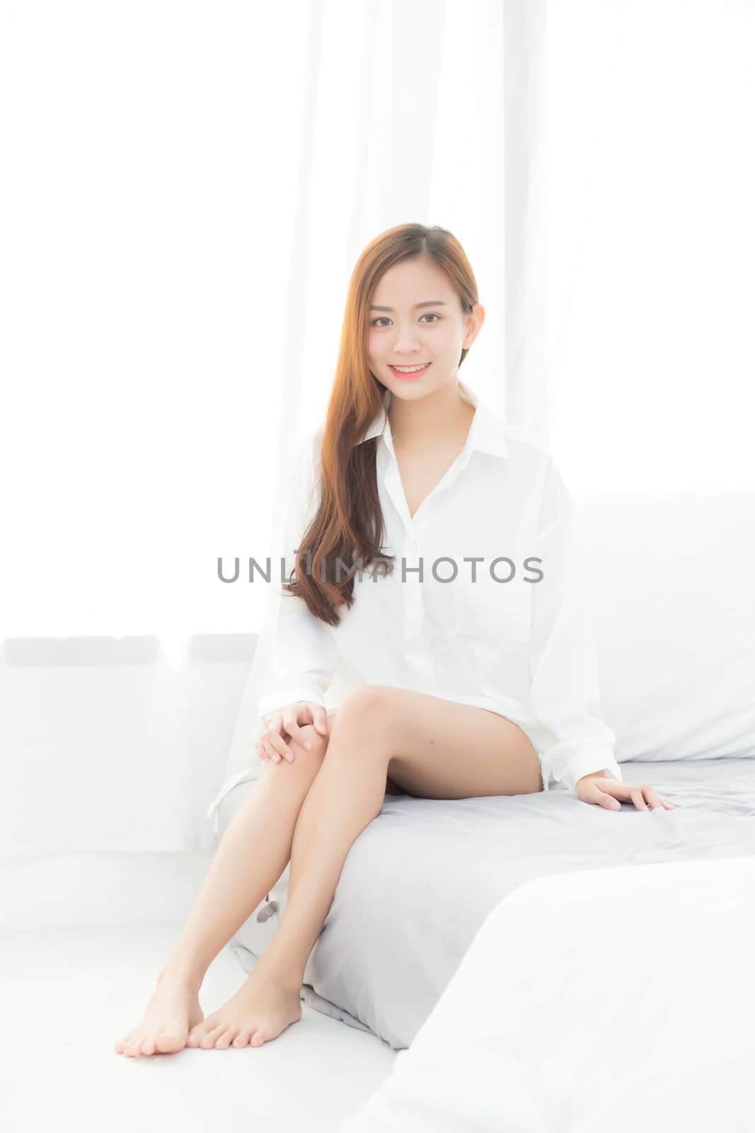 Portrait of beautiful young asian woman standing the window and smile while wake up with sunrise at morning, lifestyle and relax concept.