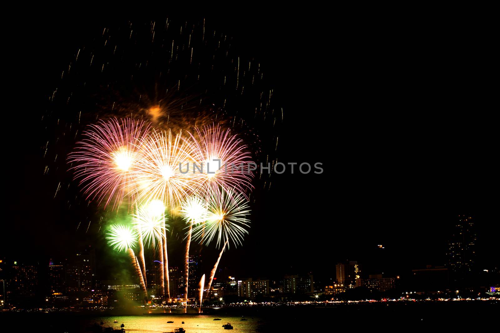 Many flashing fireworks with night cityscape background celebrate New Year.