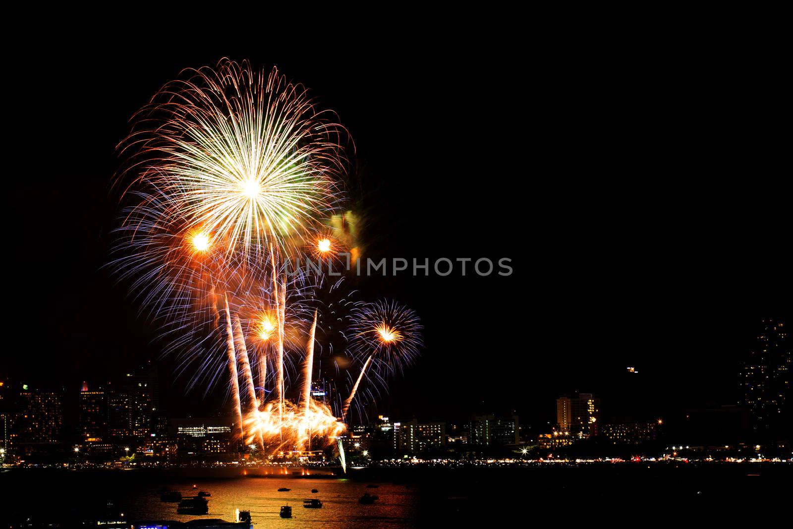 Many flashing fireworks with night cityscape background celebrate New Year.