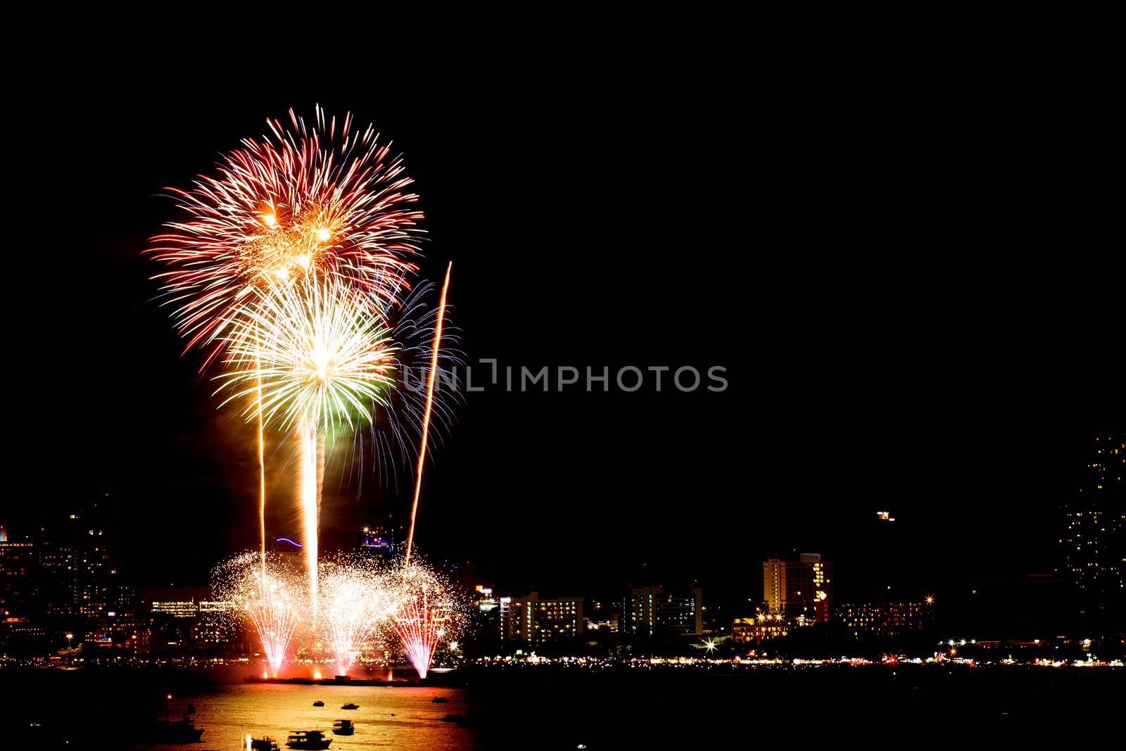 Many flashing fireworks with night cityscape background celebrate New Year.