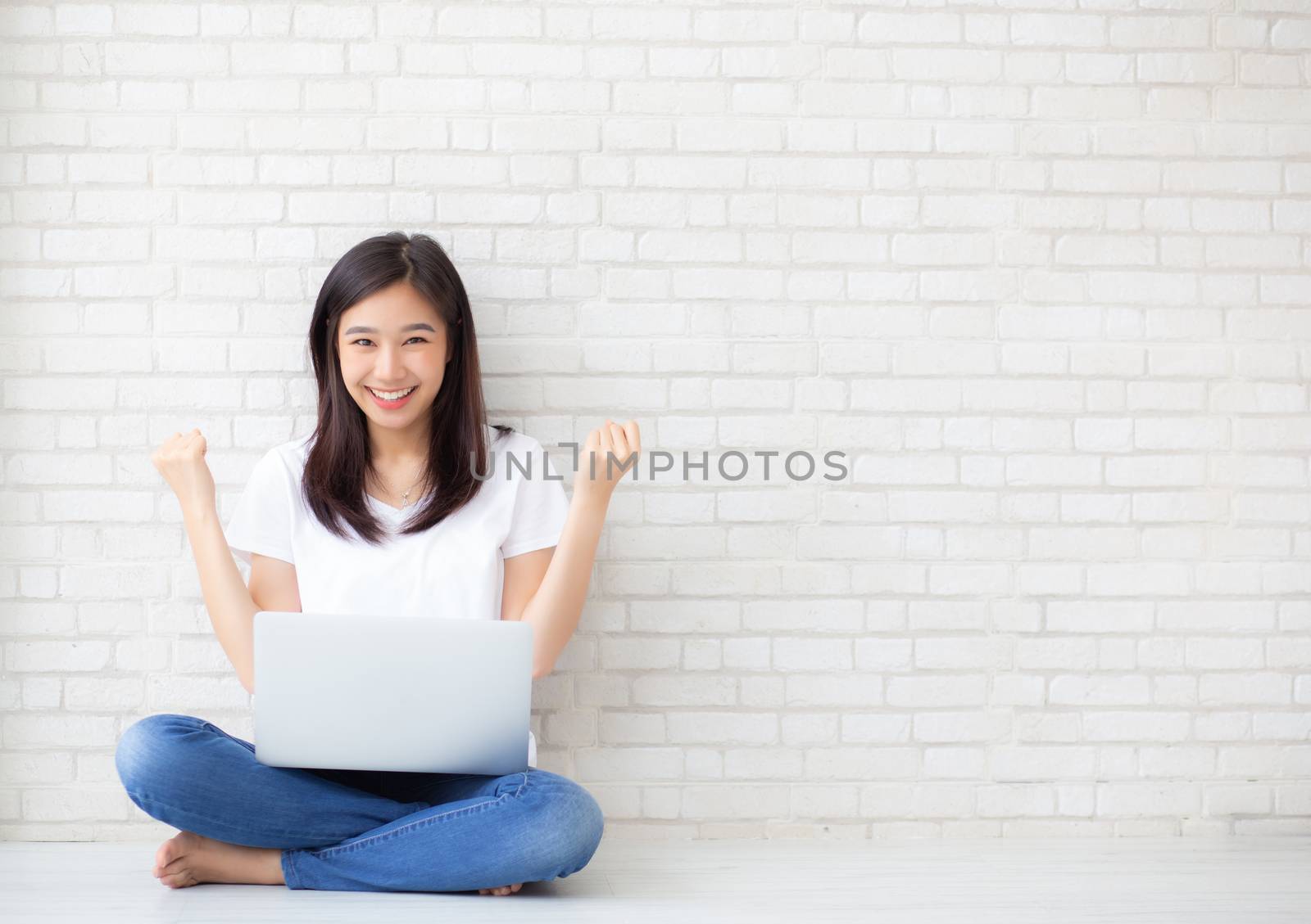 Beautiful of portrait asian young woman excited and glad of success with laptop computer, girl sitting working on cement brick background, career freelance business concept.