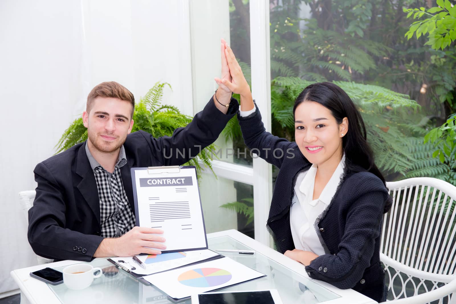 Team businesspeople hi five touching hand man and woman with smiling meeting for celebration at office, business marketing success with teamwork and graph on table.