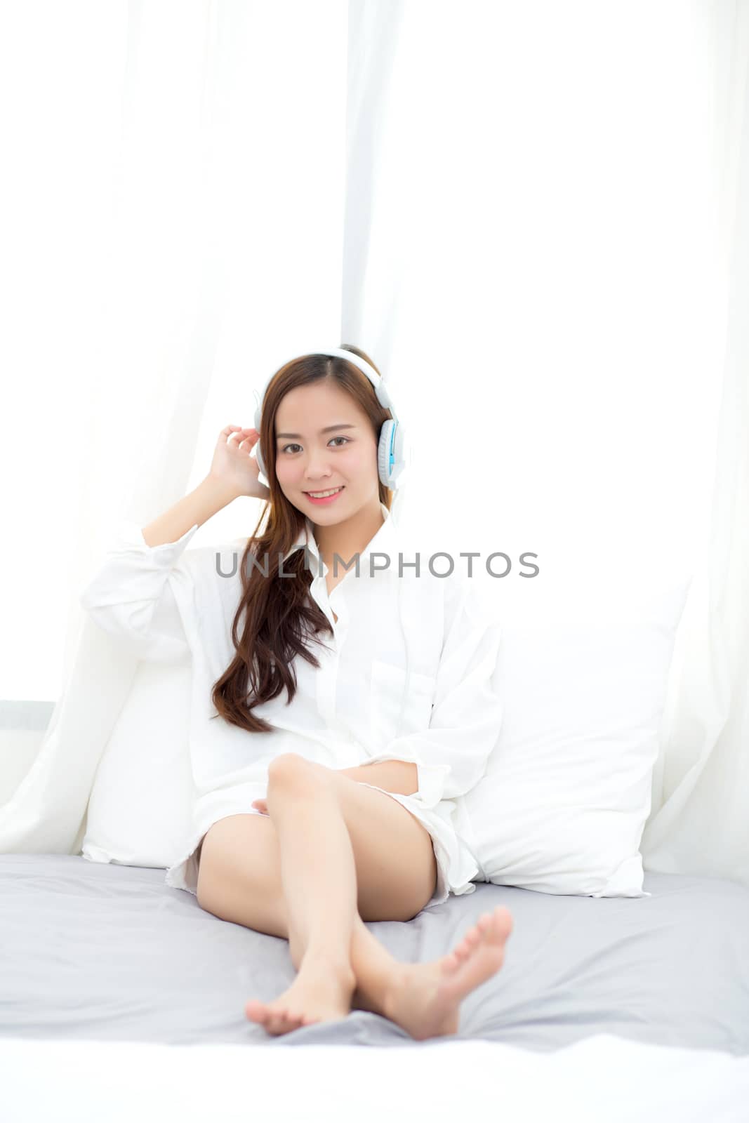 Beautiful asian young woman enjoy listen music with headphone while sitting in bedroom, relax girl with earphone internet online, leisure and technology concept.