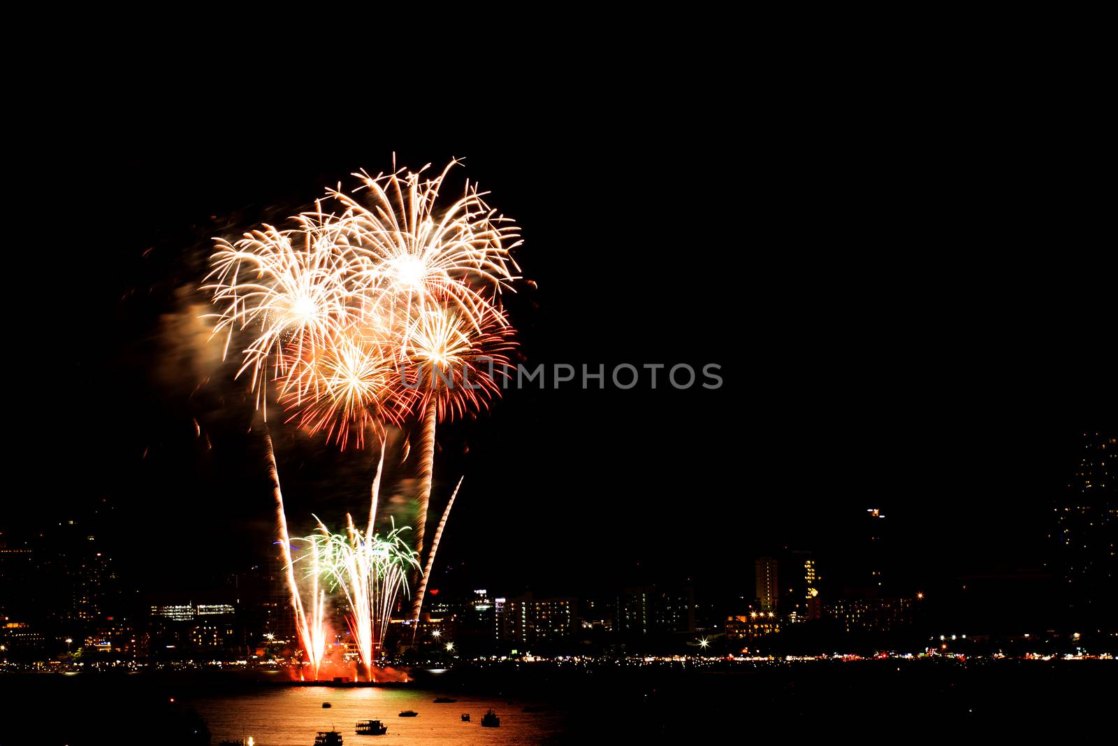 Many flashing fireworks with night cityscape background celebrate New Year.