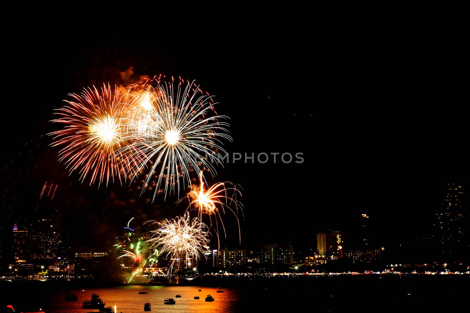 Many flashing fireworks with night cityscape background celebrate New Year.