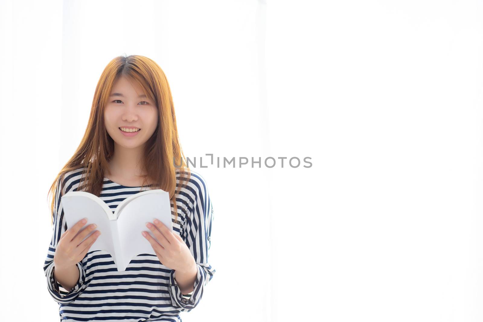 Beautiful of portrait young asian woman relax standing reading book on bedroom at home, girl study literature, education and lifestyle concept.