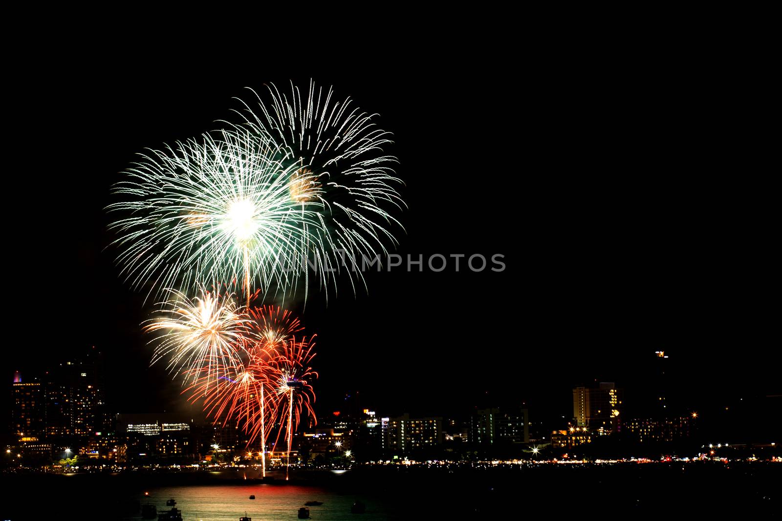 Many flashing fireworks with night cityscape background celebrate New Year.