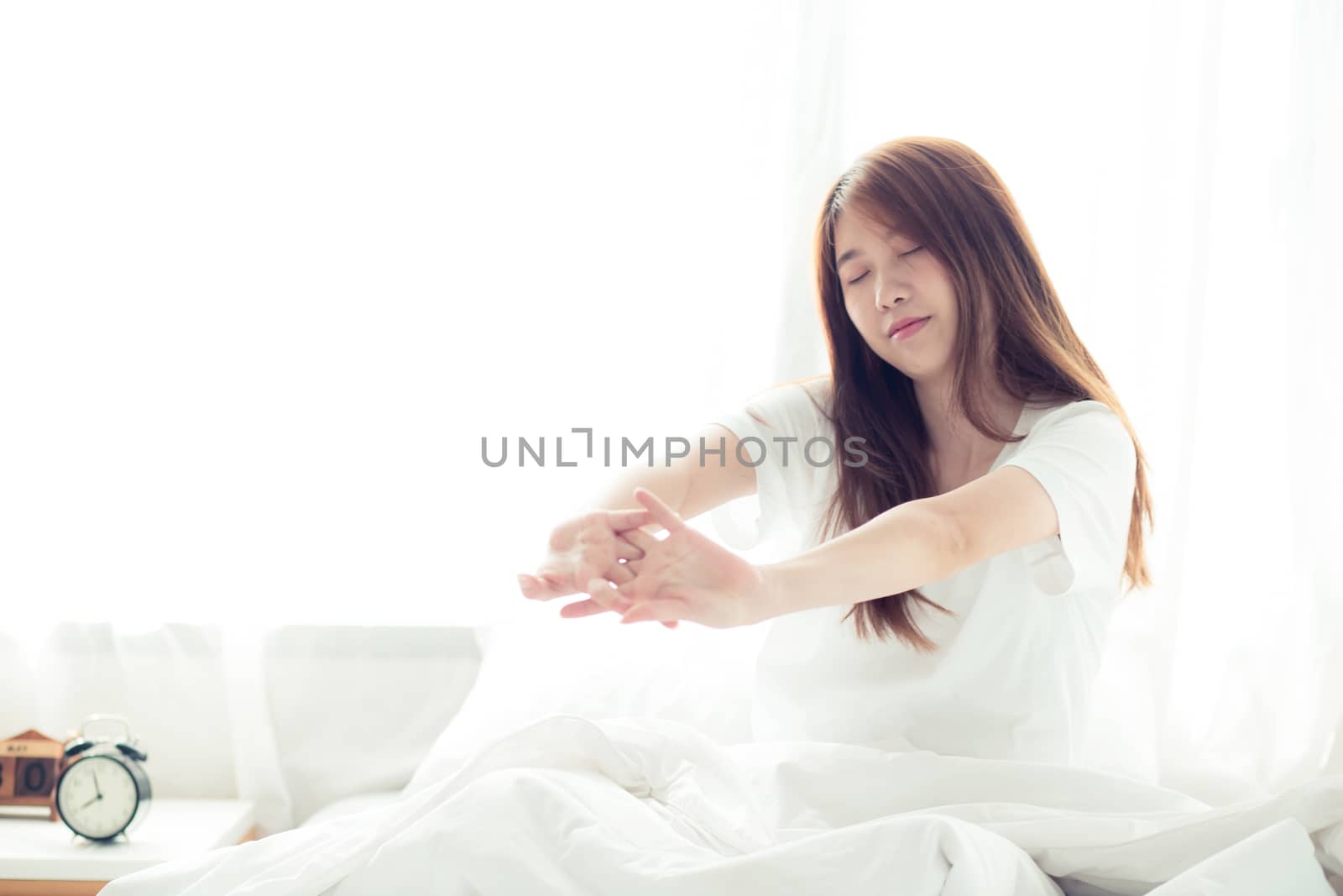 Beautiful of portrait young asian woman stretch and relax in bed after wake up morning at bedroom, new day and resting for wellness, lifestyle concept.