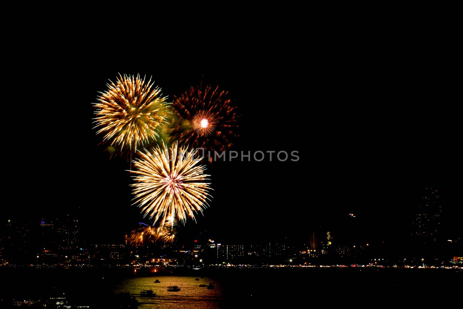 Many flashing fireworks with night cityscape background celebrate New Year.