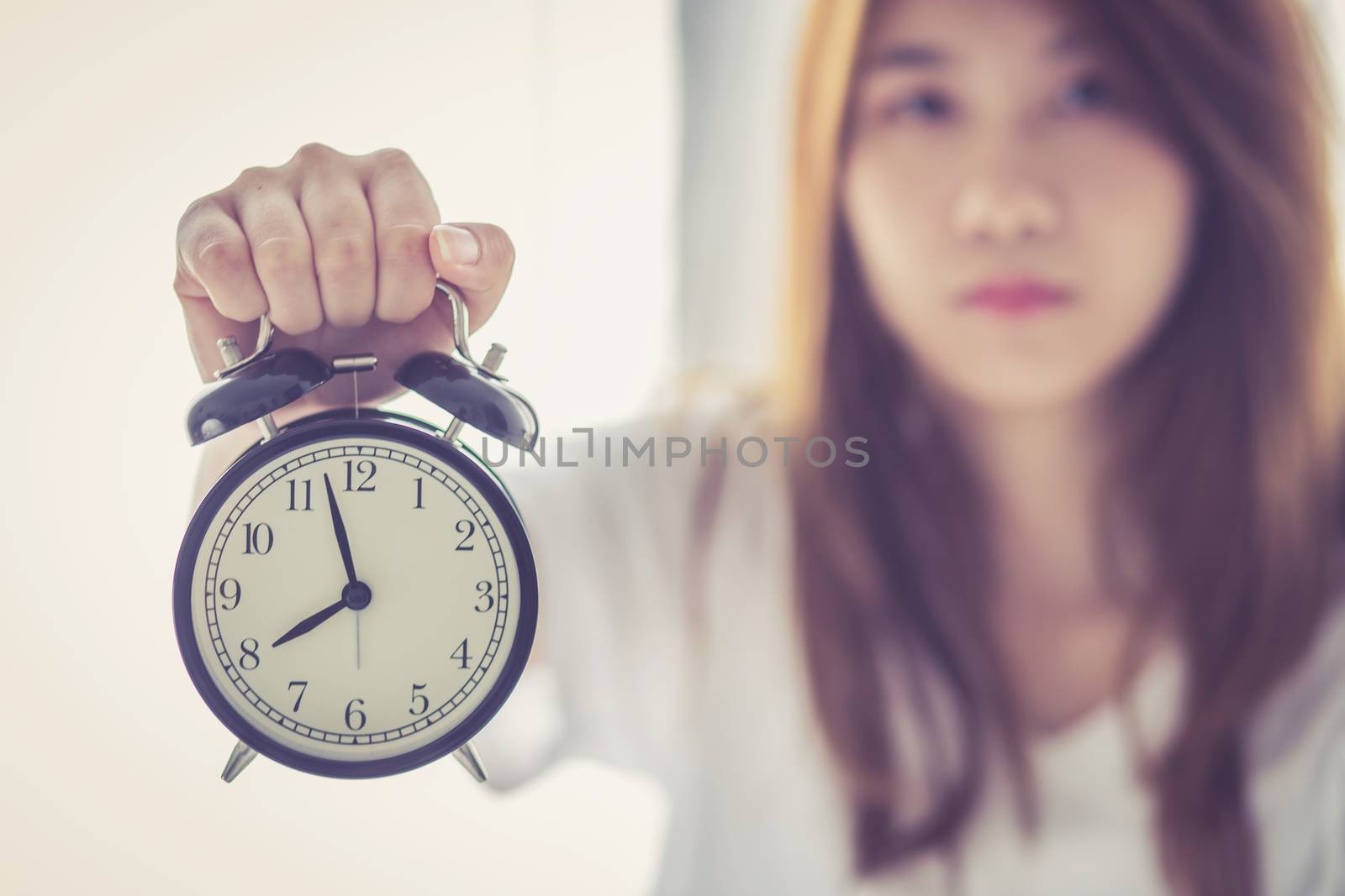 Beautiful asian young woman wake up in morning annoyed alarm clock holding hand, girl hurry wake late with appointment, lifestyle concept.
