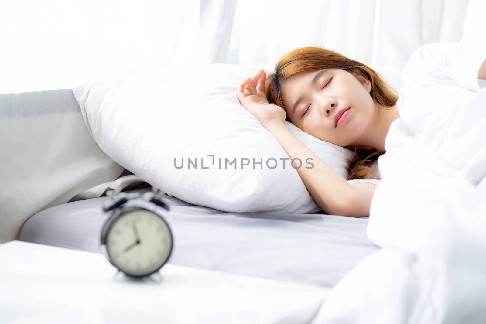 closeup alarm clock and beautiful asian young woman in morning, wake up for sleep with alarm clock, relax and lifestyle concept.