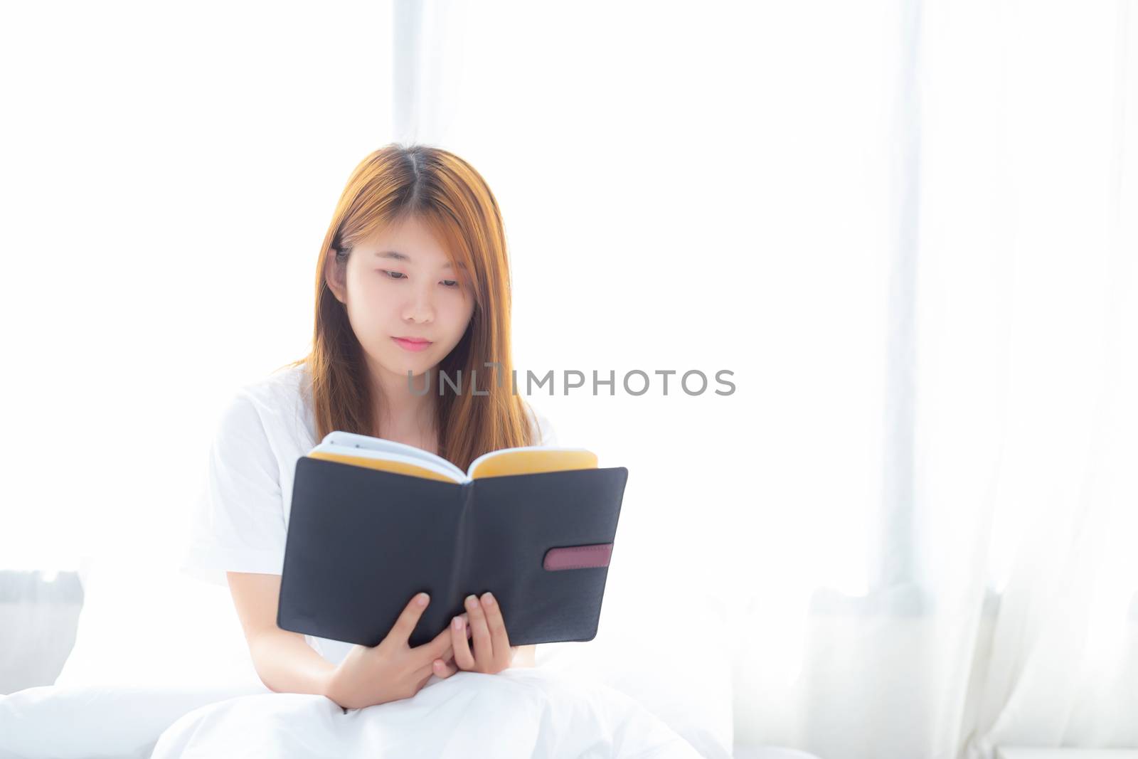 Beautiful of portrait young asian woman relax sitting reading book on bedroom at home, girl study literature, education and llifestyle concept.
