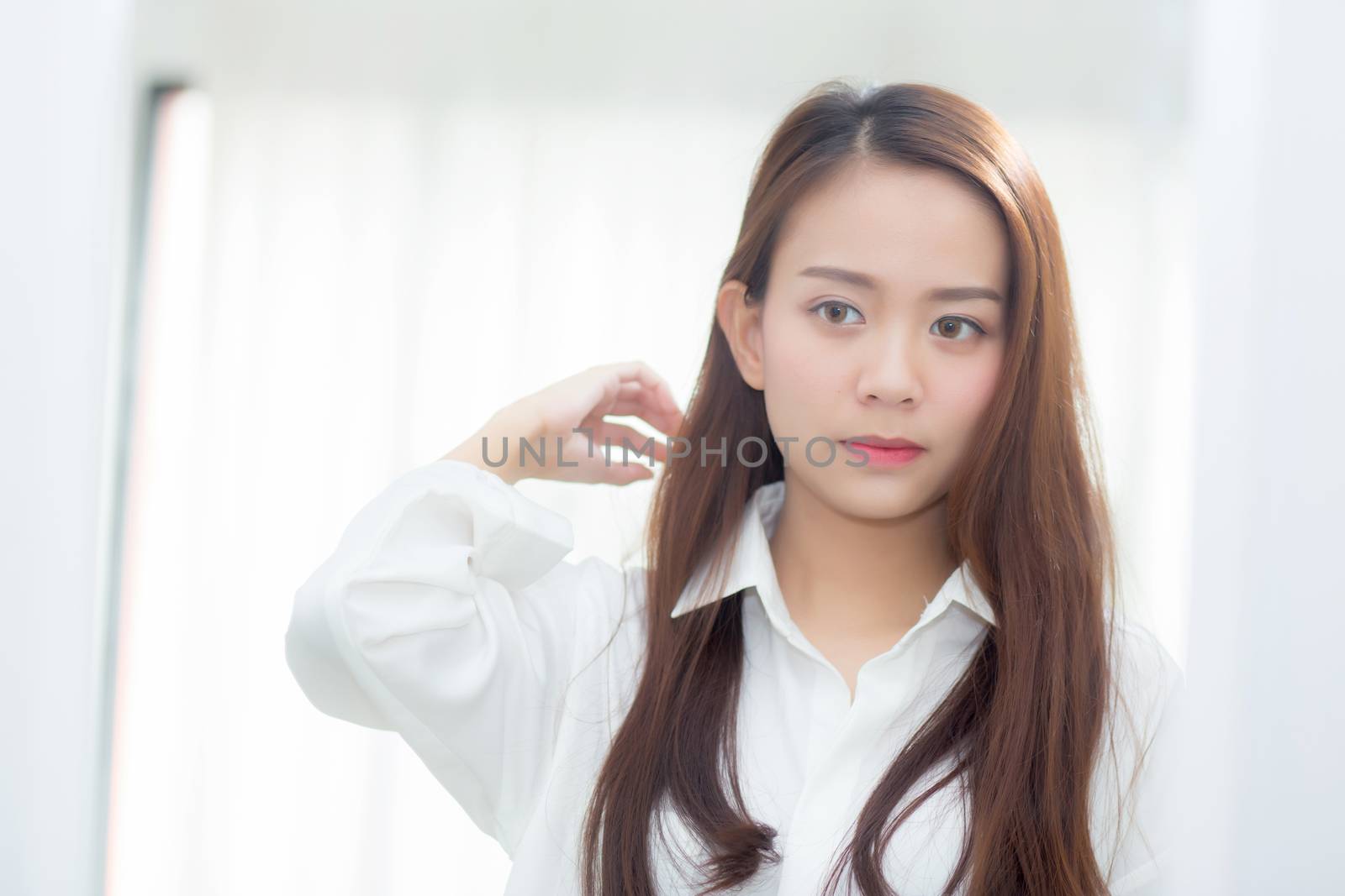 Beautiful of portrait asian young woman examining with face and smile looking on mirror at bedroom, girl beauty of makeup and dressed up with reflection, lifestyle and wellness concept.
