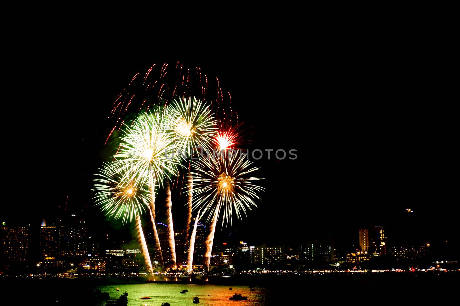 Many flashing fireworks with night cityscape background celebrate New Year.