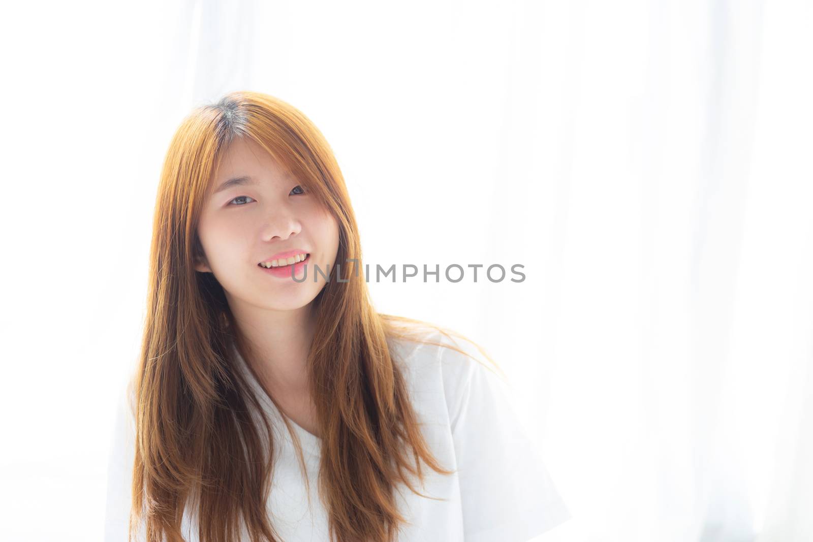Beautiful portrait young asian woman lying and smile while wake up with sunrise at morning, lifestyle and relax concept.