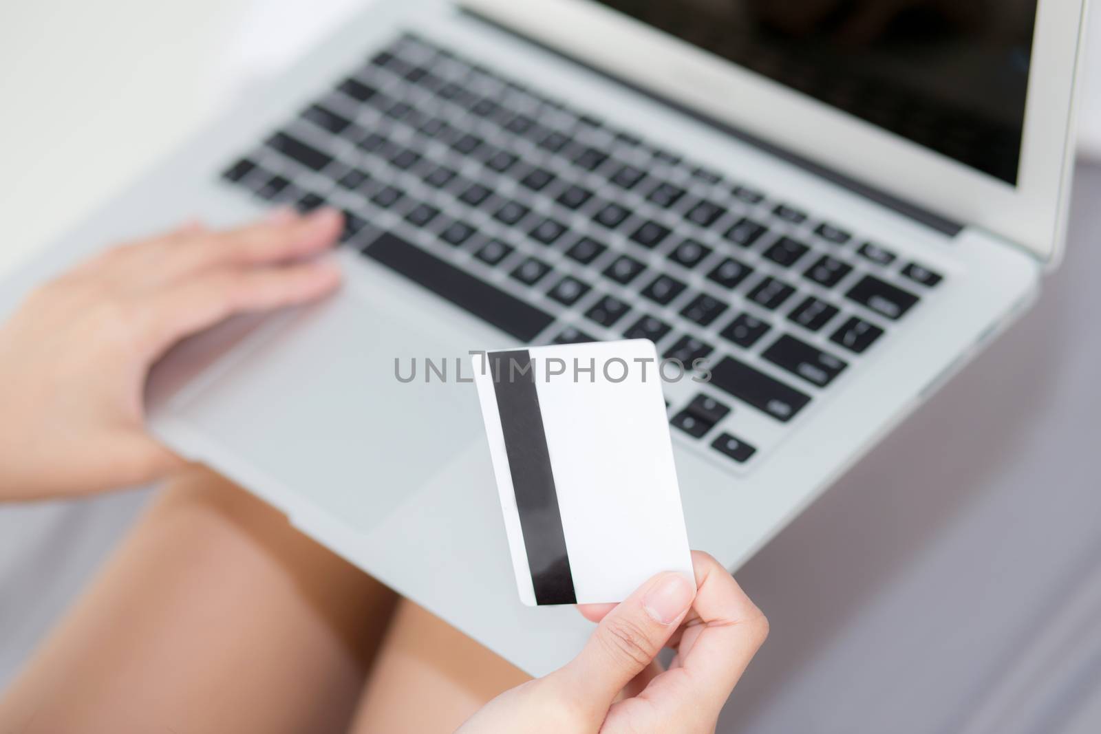 Hand holding credit card using laptop computer shopping online for web e-commerce, girl buying and pay money with debit card, finance and purchase concept.
