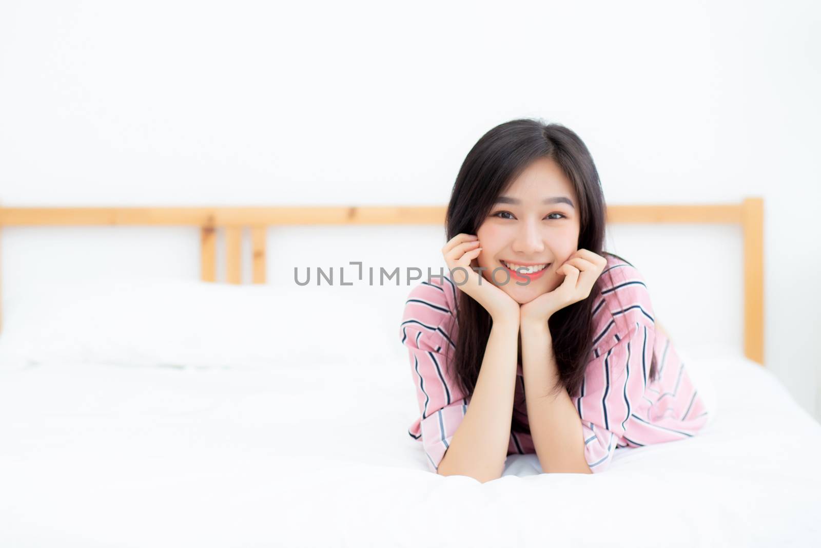 Beautiful portrait young asian woman lying and smile while wake up with sunrise at good morning, girl with happy, lifestyle and relax concept.