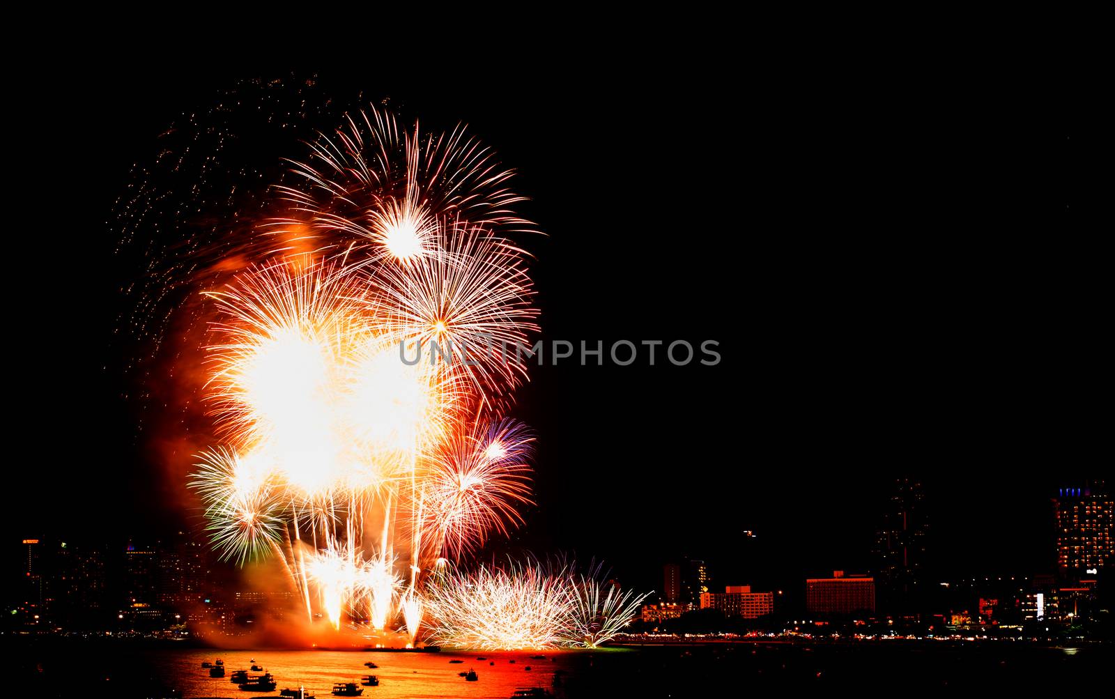 Many flashing fireworks with night cityscape background celebrate New Year.