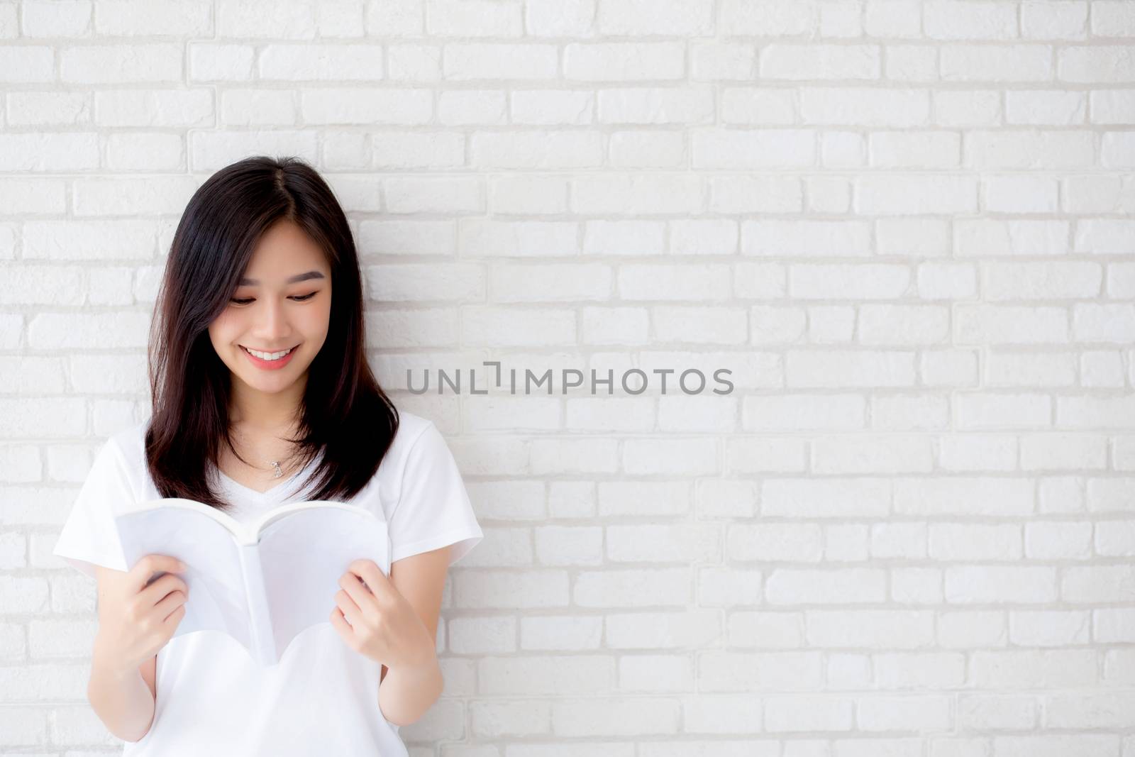 beautiful portrait young asian woman happy open the book with cement or concrete background, lifestyle of girl standing reading study for learning, education and knowledge concept.