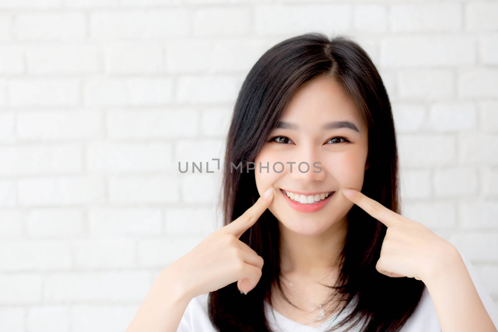 Portrait of beautiful young asian woman happiness standing finger touch cheek on gray cement texture grunge wall brick background, businesswoman is a smiling on concrete, business people concept.