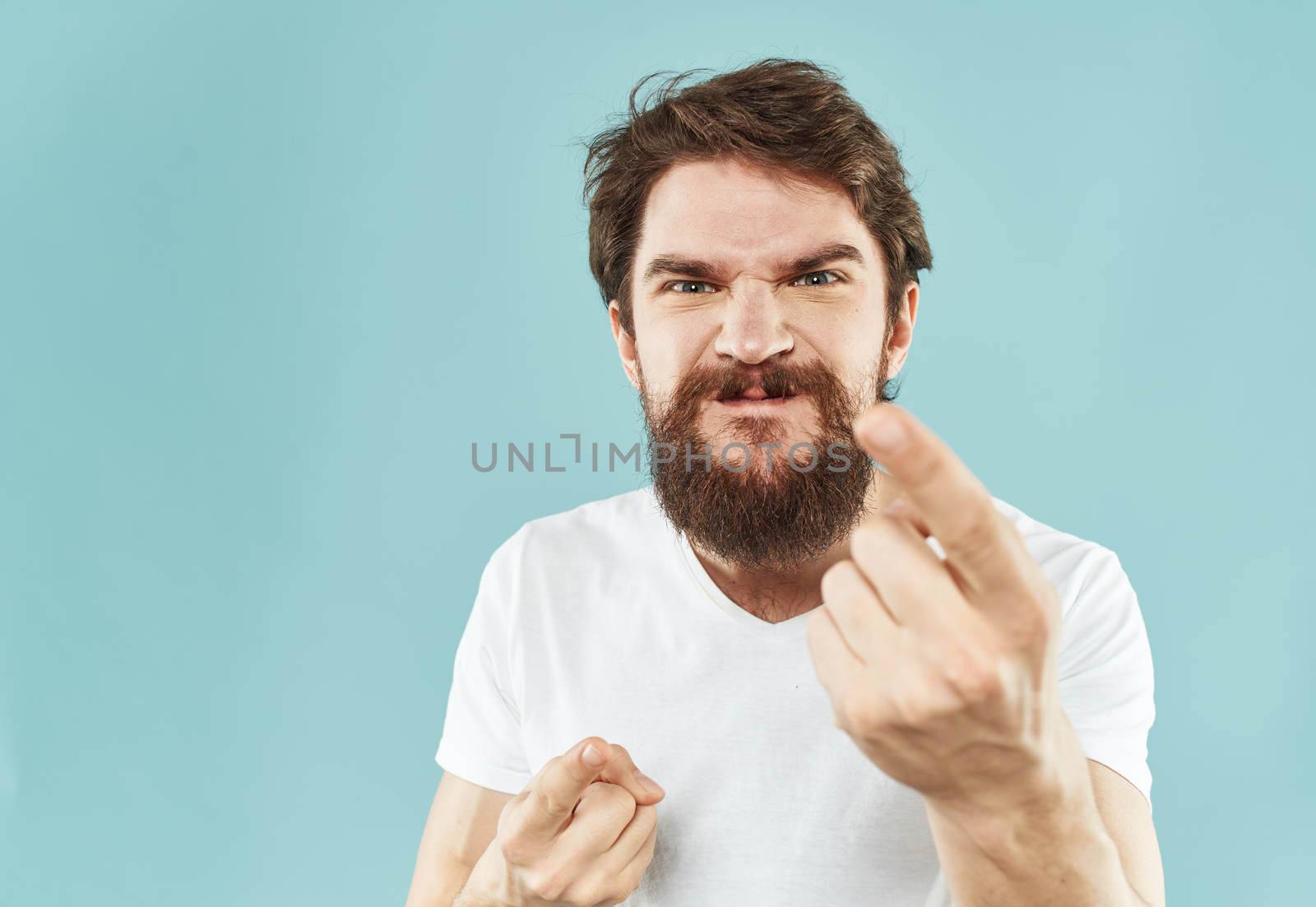 Model bearded man in white T-shirt on blue background irritability emotions model. High quality photo