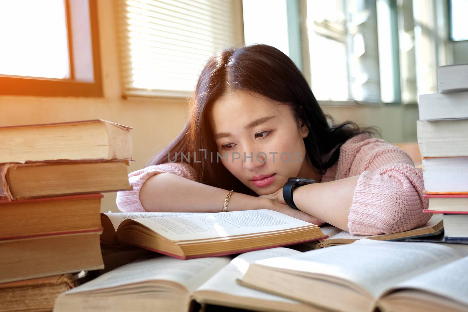 Young woman sleeping in library by Surasak