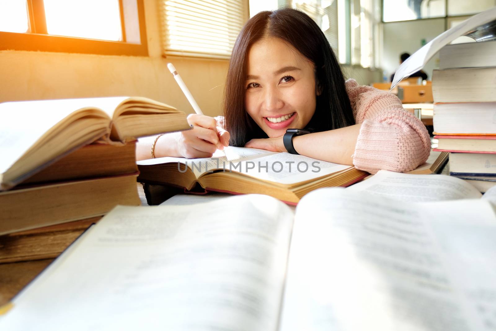 Young woman taking note and studying in library by Surasak