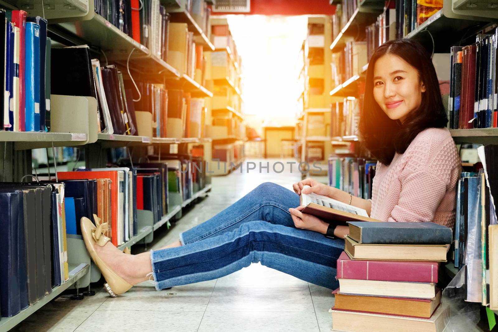 Young woman studying in a library by Surasak