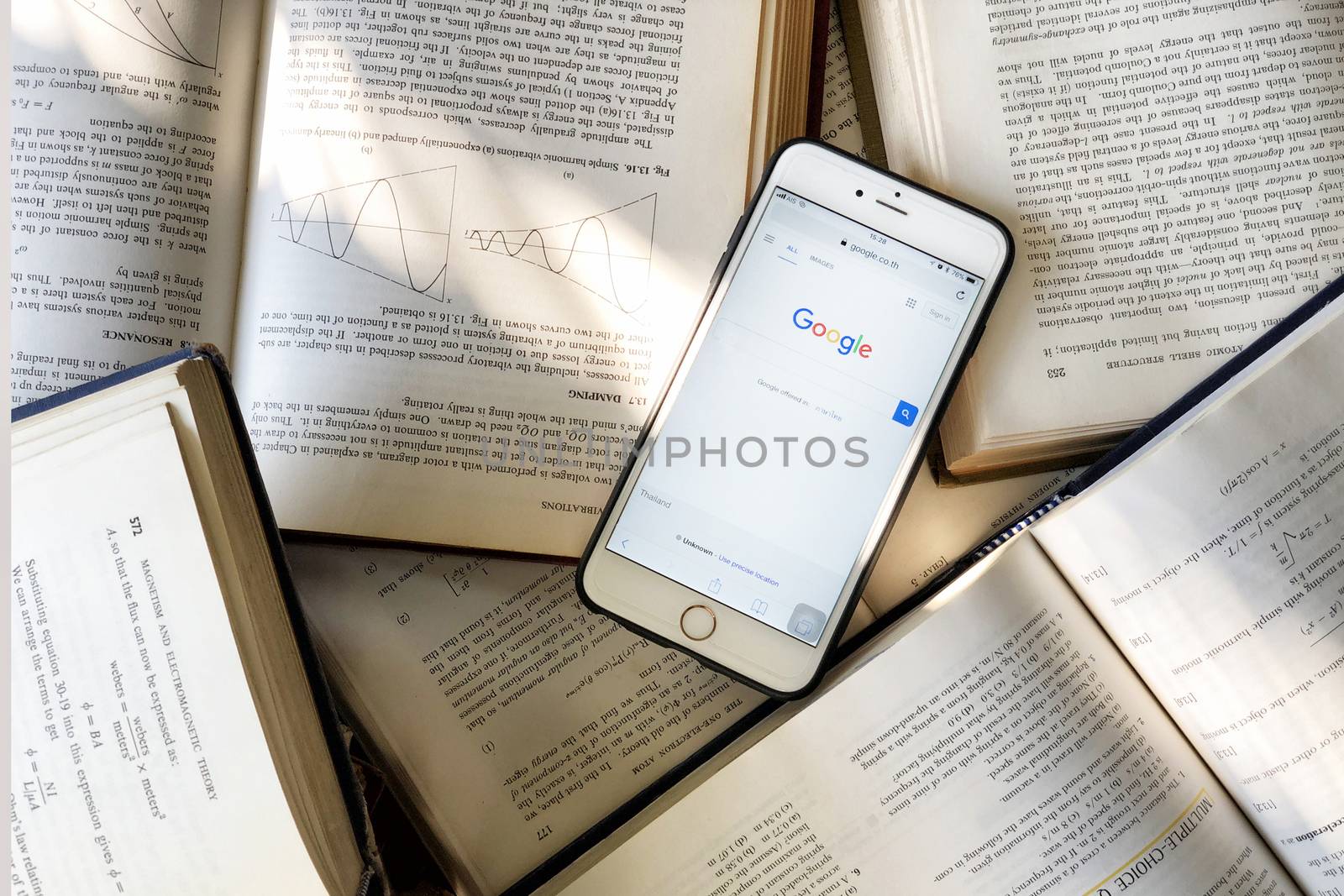 Bangkok, Thailand - 21 February: Close up the new and old student tools for information seeking, using the most popular internet search engine "Google Web Browser" on smartphone and using the old model of reading books in library.